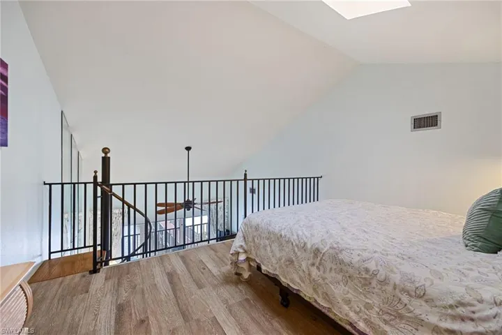 Bedroom featuring a skylight, wood finished floors, and vaulted ceiling