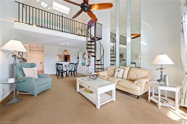 Carpeted living room featuring a towering ceiling, stairs, ceiling fan, a skylight, and recessed lighting