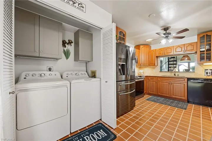 Kitchen featuring glass insert cabinets, backsplash, dark tile patterned floors, and stainless steel appliances