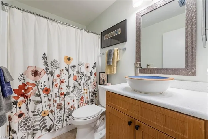 Full bathroom with vanity, light tile patterned floors, and a shower with shower curtain