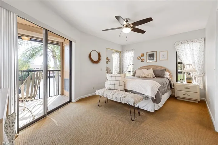 Carpeted bedroom with multiple windows, access to exterior, and ceiling fan