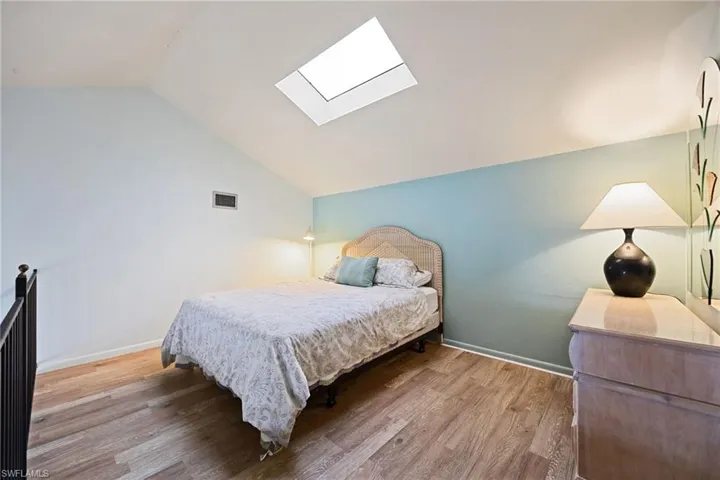 Bedroom with a skylight, lofted ceiling, and light wood-style floors
