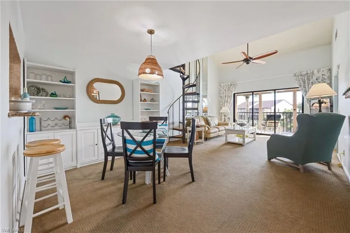 Dining area featuring built in shelves, light carpet, stairs, and a ceiling fan