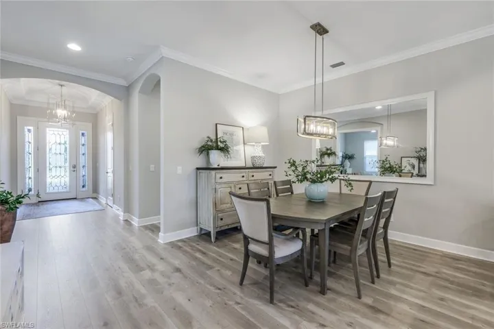 Dining space with a notable chandelier, ornamental molding, and hardwood / wood-style flooring