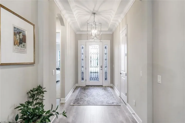 Entryway with a tray ceiling, crown molding, and hardwood / wood-style floors