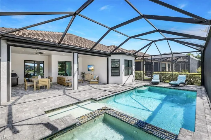 View of pool featuring outdoor lounge area, a patio, an in ground hot tub, glass enclosure, and ceiling fan