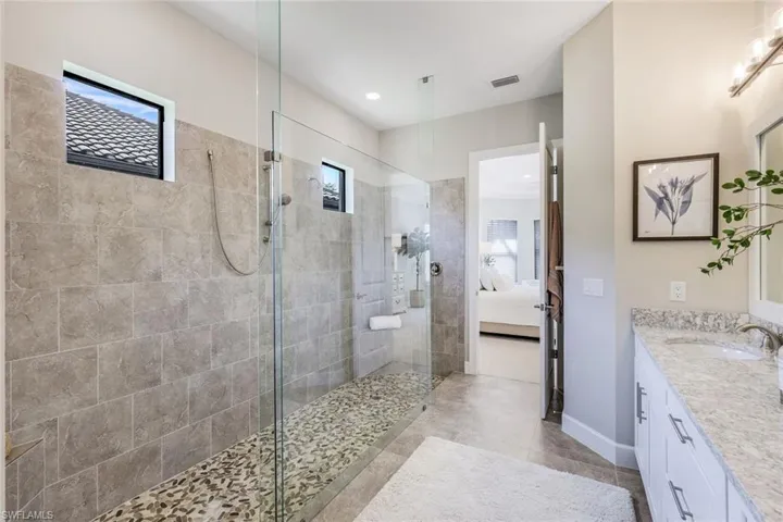 Bathroom featuring oversized vanity, tile floors, and a shower with door