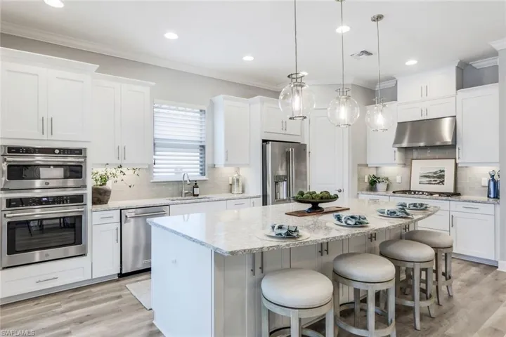 Kitchen featuring tasteful backsplash, stainless steel appliances, light wood-type flooring, sink, and white cabinets