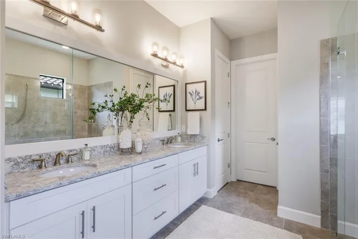 Bathroom featuring a tile shower, oversized vanity, dual sinks, and tile floors