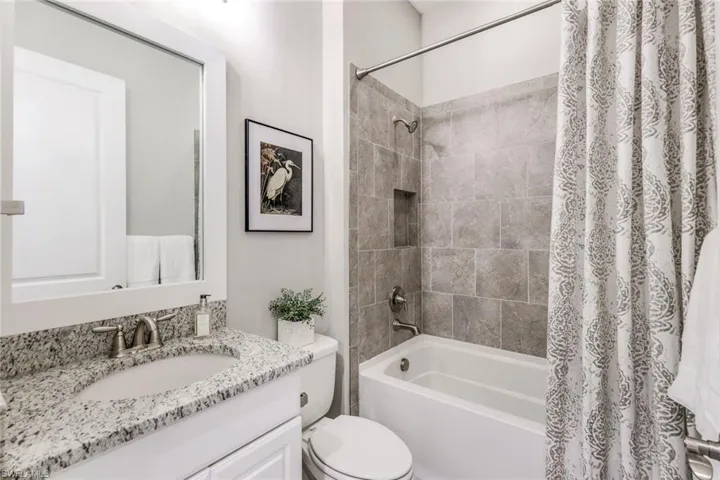 Full bathroom featuring shower / bathtub combination with curtain, oversized vanity, and toilet
