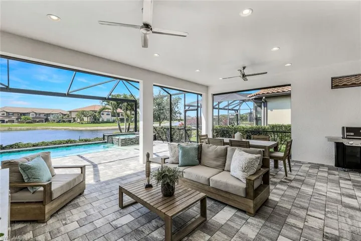 Sunroom with ceiling fan, a water view, and a pool