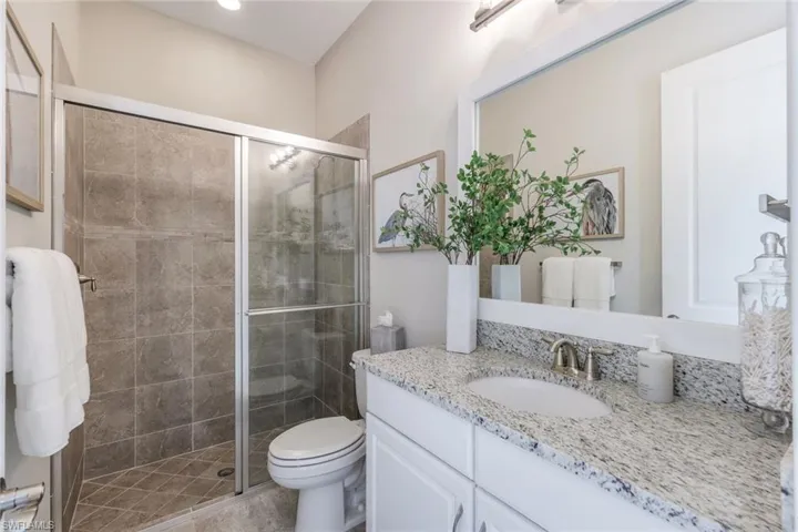Bathroom with an enclosed shower, oversized vanity, and toilet