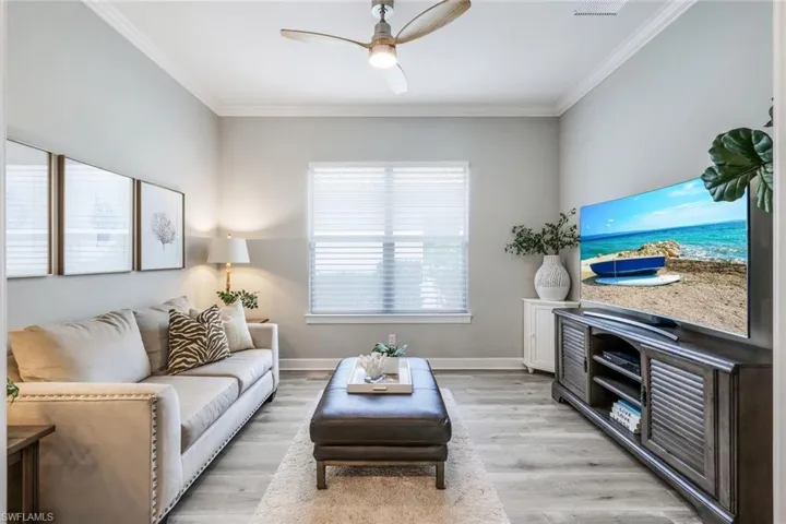 Living room featuring ornamental molding, light wood-type flooring, and ceiling fan