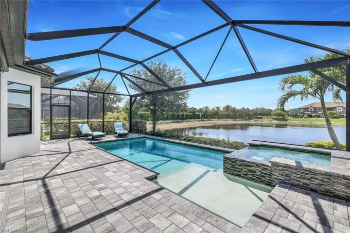 View of pool with a patio, a lanai, an in ground hot tub, and a water view