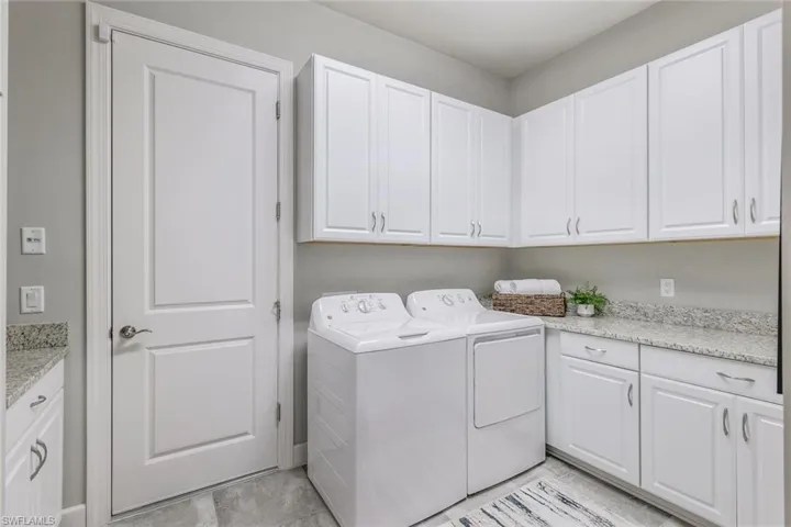 Laundry area featuring washer and clothes dryer, cabinets, and light tile flooring