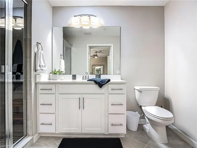 Full bathroom with marble finish floors, vanity, a ceiling fan, and an enclosed shower