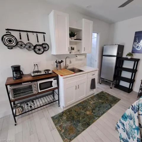 Kitchen featuring white cabinets, light hardwood / wood-style flooring, stainless steel refrigerator, and sink