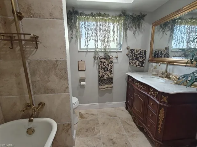 Bathroom featuring tile patterned floors, vanity, toilet, and a tub