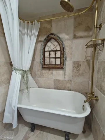Bathroom featuring tile patterned flooring and tile walls