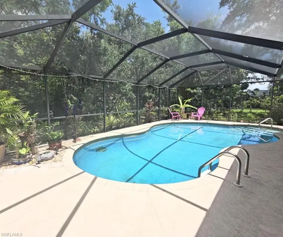 View of pool featuring a patio and glass enclosure