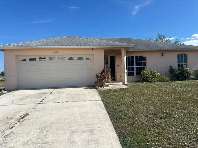 Single story home with a garage and a front lawn