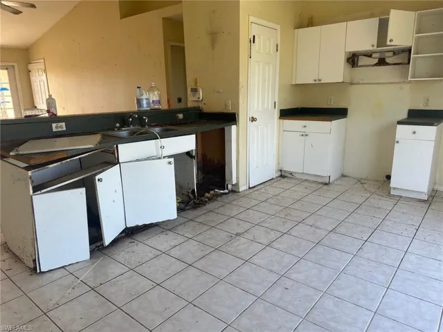 Kitchen with ceiling fan, white cabinetry, and sink