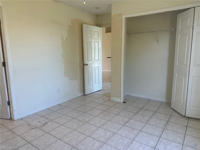 Unfurnished bedroom with a closet and light tile patterned flooring