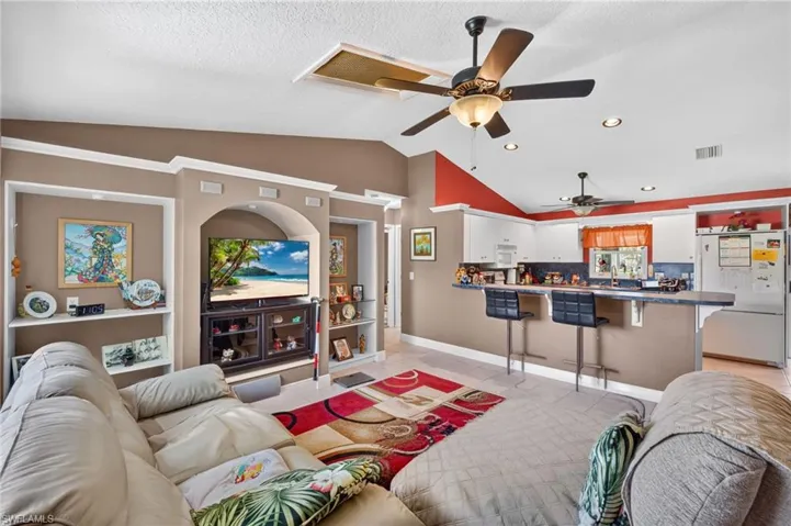 Open-concept living space featuring vaulted ceilings, recessed lighting, and tile flooring