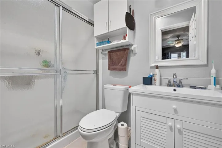 Primary bathroom featuring a white vanity with a built-in sink, framed mirror, built-in shelving, and a shower with sliding glass doors