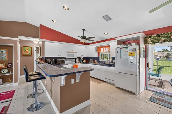 Kitchen featuring white cabinetry, a breakfast bar with a laminate countertop, recessed lighting, and tile flooring