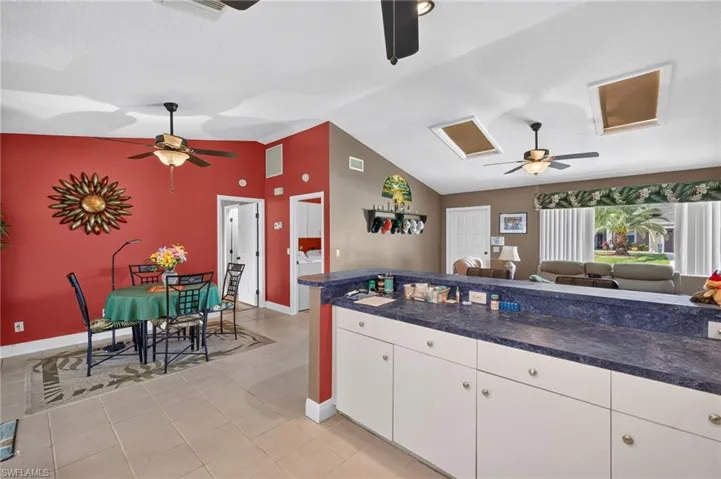 Open-concept living space with vaulted ceilings, skylights, and tile flooring
