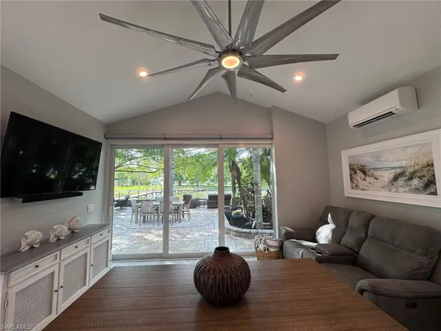 Living room featuring ceiling fan, hardwood / wood-style flooring, a wall mounted AC, and lofted ceiling