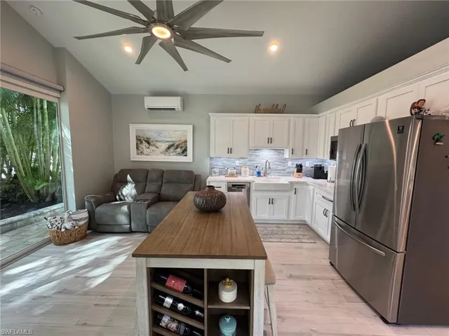 Kitchen featuring wooden counters, light hardwood / wood-style floors, white cabinetry, appliances with stainless steel finishes, and an AC wall unit