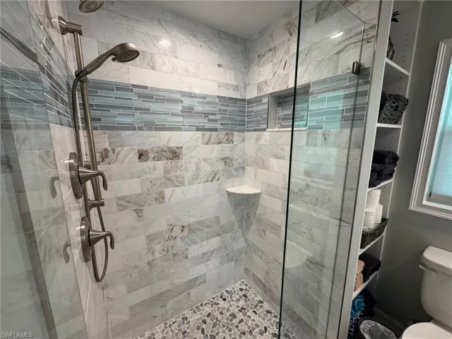 Bathroom featuring tiled shower and toilet