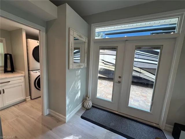 Doorway to outside with stacked washer and dryer, light hardwood / wood-style flooring, and french doors