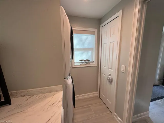 Laundry area featuring stacked washing maching and dryer and light hardwood / wood-style flooring