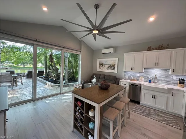 Kitchen with white cabinetry, sink, light hardwood / wood-style floors, dishwasher, and lofted ceiling