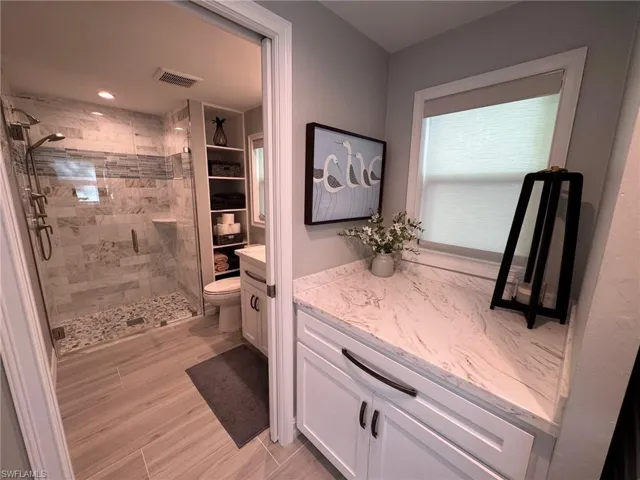 Bathroom with toilet, vanity, and a shower with shower door