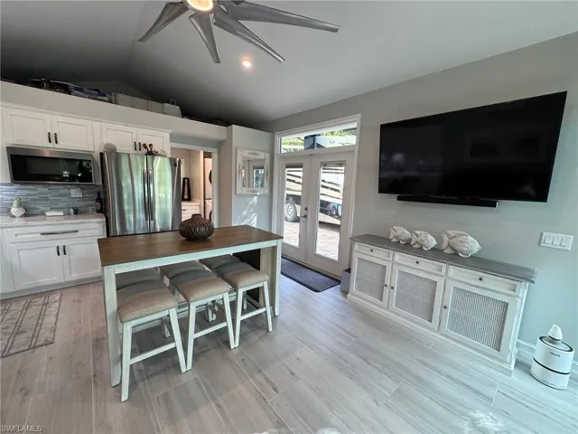 Kitchen featuring stainless steel appliances, vaulted ceiling, light hardwood / wood-style flooring, white cabinets, and french doors