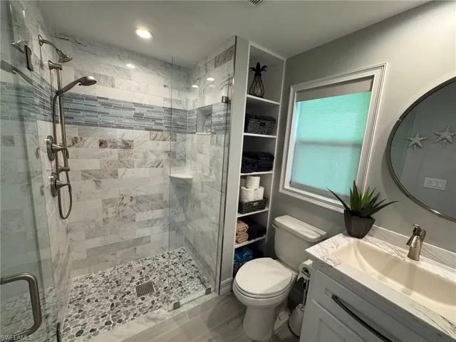 Bathroom featuring toilet, vanity, wood-type flooring, and a shower with shower door