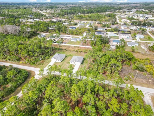 Aerial perspective featuring cleared residential lots with asphalt road access and surrounding wooded acreage