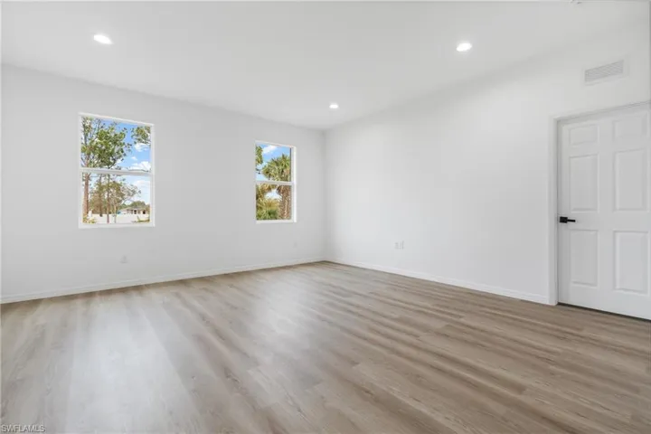 Interior space featuring wood-finish flooring, recessed lighting, and a six-panel door with matte black hardware