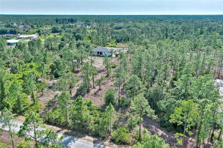 Aerial view of property and surrounding area with a heavily wooded area