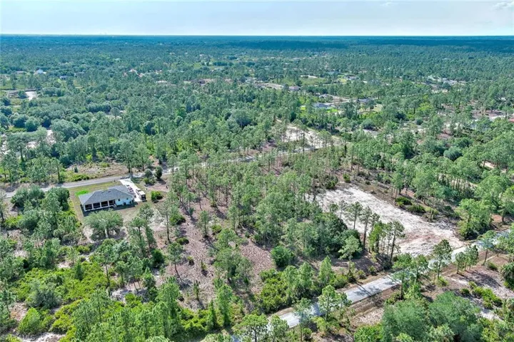 Aerial view of property and surrounding area featuring a forest