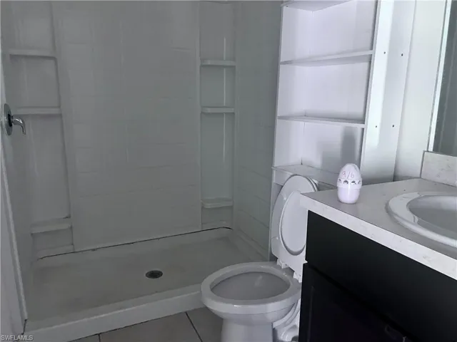 Bathroom with walk in shower, vanity, toilet, and tile patterned floors