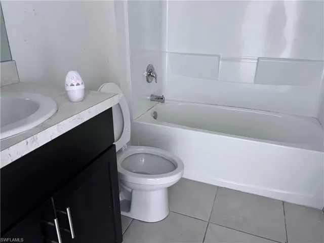 Full bathroom with shower / bathing tub combination, vanity, toilet, and tile patterned floors