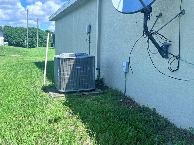 View of side of home with central AC unit and a yard