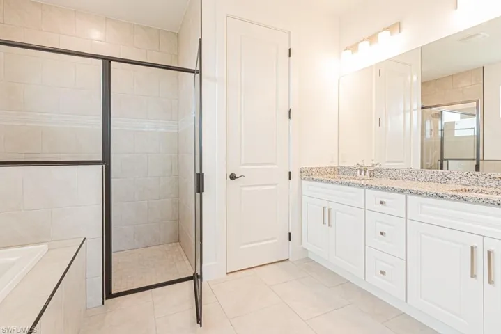 Full bath featuring a shower stall, double vanity, a bath, and tile patterned floors