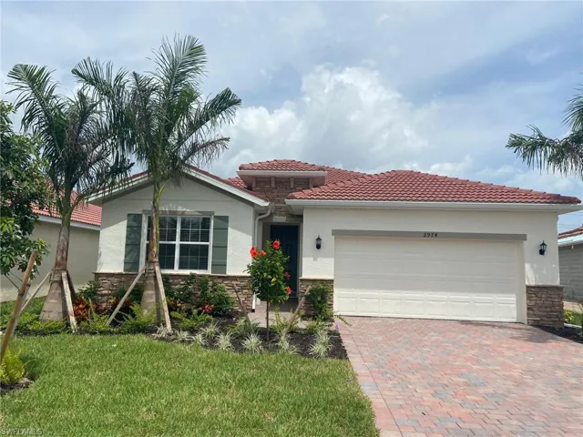 View of front of home featuring stone siding, stucco siding, decorative driveway, and an attached garage