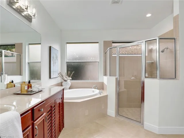 Bathroom with tile patterned flooring, vanity, and separate shower and tub